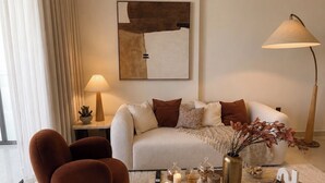 A modern living room with a sofa, armchair, coffee table, and a lamp.
