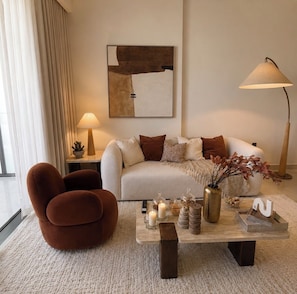 Una sala de estar moderna con sofá, sillón, mesa de centro y lámpara.