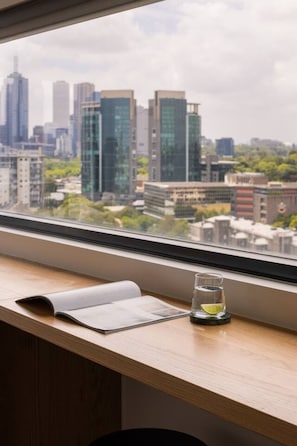 A window with a view of a cityscape, a notebook, and a glass with a lime slice on a wooden desk. - 2BD | Immaculate SkyHigh Apartment |Prime Location (Southbank)