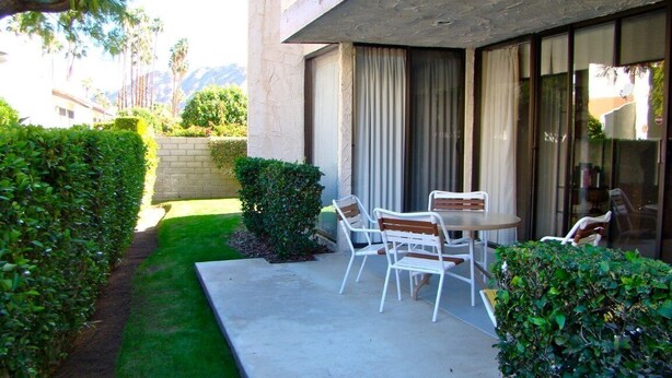 A patio with a table and chairs, a small hedge, and a building with a window. - two bedrooms, two bathrooms, a full kitchen, living and dining areas. (Palm Springs)