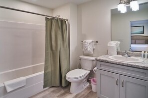 A bathroom with a shower curtain, toilet, sink, and mirror. - The Ruby 207 (Pigeon Forge)