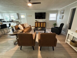 A modern living room with a sofa, two armchairs, a coffee table, and a TV. - Sunny Days at the Gorge 
Your Red River Gorge Adventure Basecamp (Rogers)