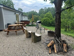 Ein überdachter Außenbereich mit Picknicktischen, einem Grill und einem Whirlpool.