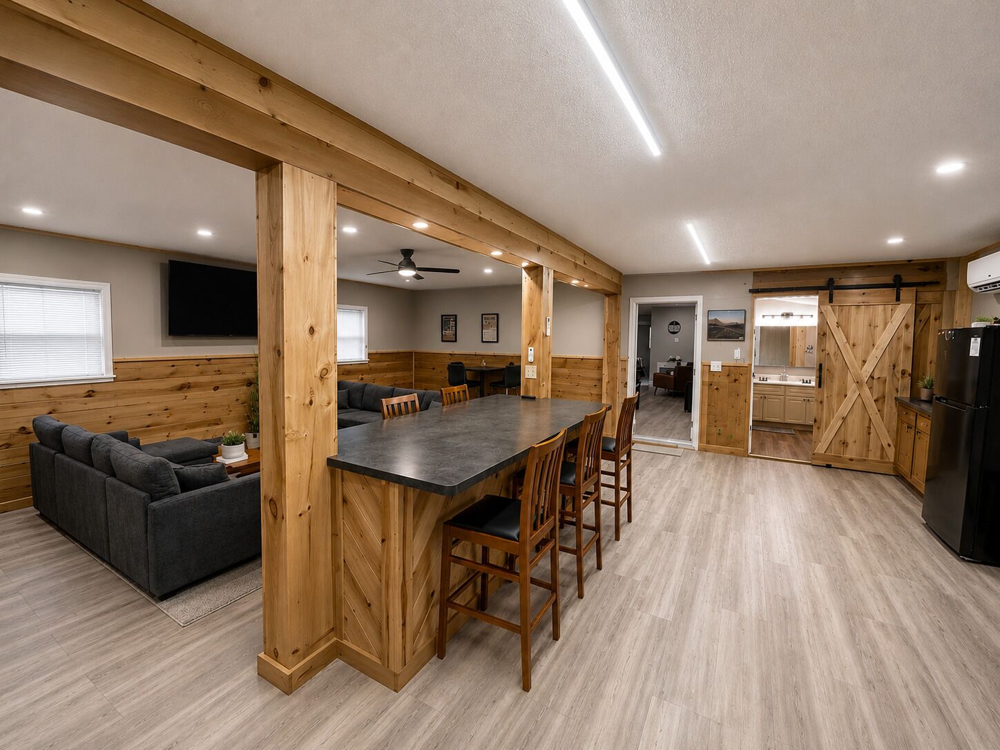 Amplia sala de estar con una pared de acento de madera, una mesa de comedor y una cocina con una puerta corrediza estilo granero.