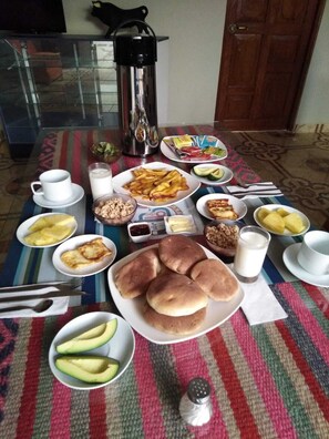 A dining table with various breakfast items including pancakes, eggs, and avocado. - Samaykuy (Urubamba)
