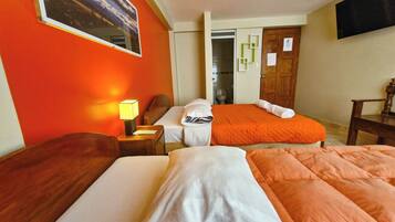 Une chambre d’hôtel avec deux lits, une table de chevet, une lampe, une chaise en bois, un téléviseur fixé au mur et une porte avec un miroir.