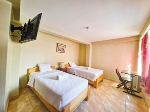 A hotel room with two beds, a TV mounted on the wall, a small table, and a chair. - Samaykuy (Urubamba)