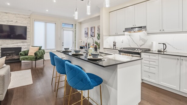Una cucina moderna con isola centrale, sgabelli da bar e piano cottura integrato.