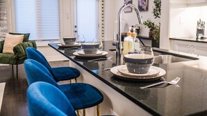 Una cucina moderna con isola centrale, sgabelli da bar e zona pranzo con divano verde.