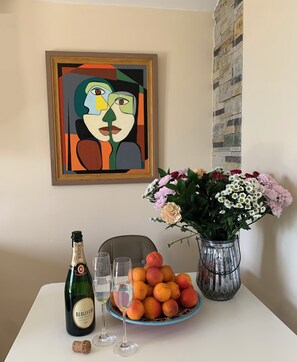 A table with a bottle of champagne, glasses, a plate of peaches, and a vase of flowers. - Vacation apartment in Montenegro. Quiet location near the sea. Welcome! (Bar)