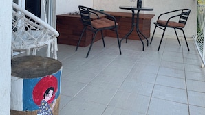 Un balcon avec une table et des chaises, un fauteuil suspendu et une vue sur le paysage.