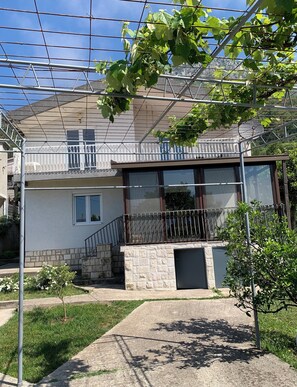 A residential building with a balcony, a stone staircase, and a small garden area. - Vacation apartment in Montenegro. Quiet location near the sea. Welcome! (Bar)