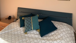 Une chambre à coucher avec un lit, des oreillers, un tableau accroché au mur et des panneaux décoratifs.