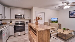 Een moderne keuken met witte kastjes, een ingebouwde oven en een eethoek met een houten tafel en stoelen.