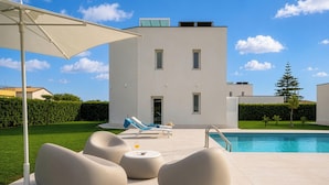 Un edificio moderno con piscina, mobiliario exterior y cielo despejado.