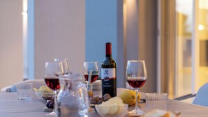Una mesa de comedor con copas de vino, una botella de vino y un bol de aperitivos.