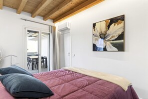A bedroom with a bed, a painting, and a sliding door leading to a dining area. - Lake Garda Nidesti Suite Apartment (DESENZANO DEL GARDA)