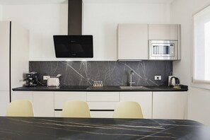 A modern kitchen with a black countertop, white cabinets, a built-in microwave, and a black range hood. - Lake Garda Nidesti Suite Apartment (DESENZANO DEL GARDA)