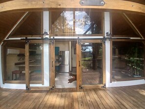 Um deck de madeira com entrada por porta de vidro que dá para uma cozinha.