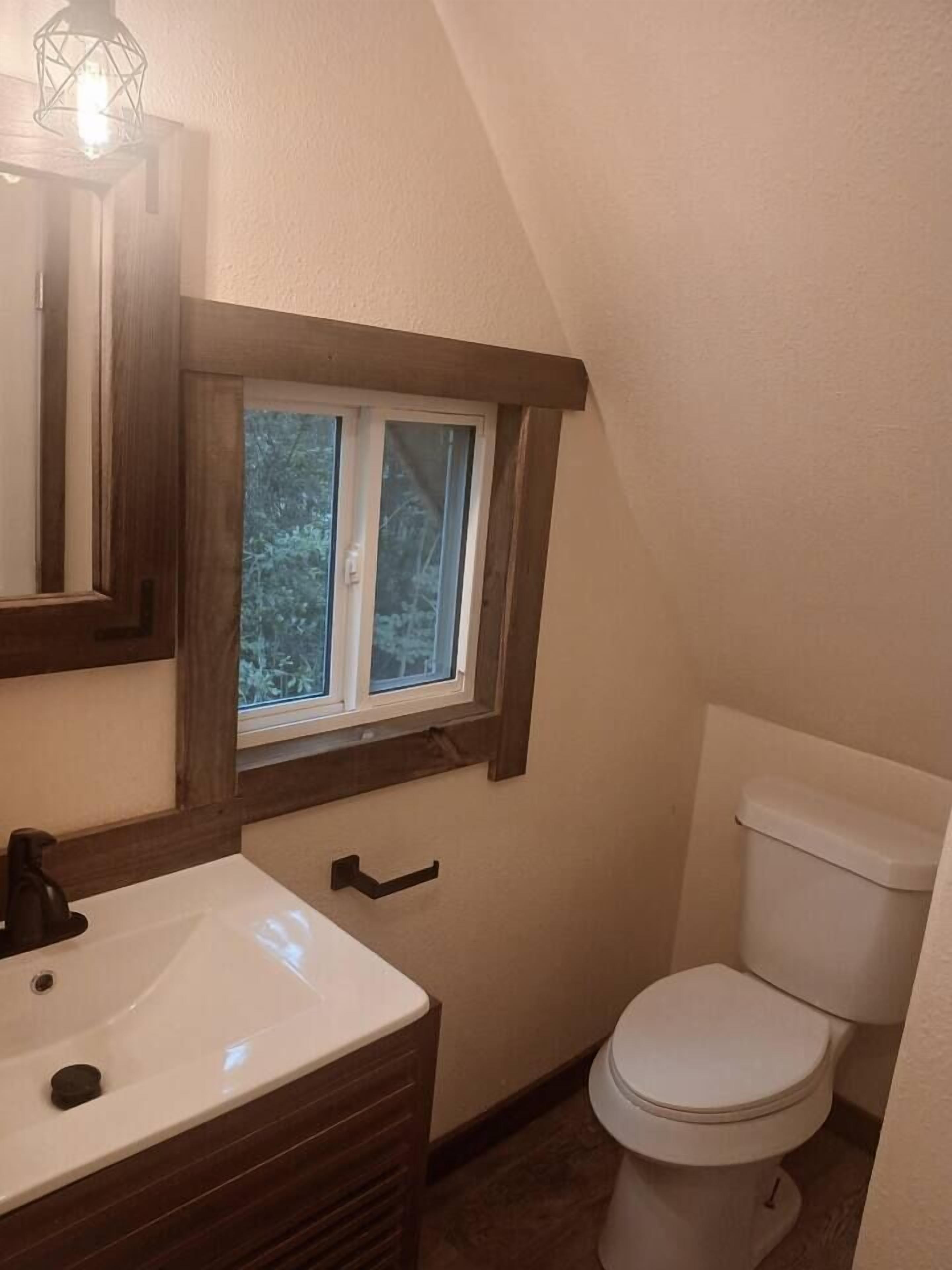 A small bathroom with a window, a sink, and a toilet.