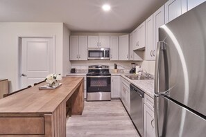 A modern kitchen with stainless steel appliances, white cabinetry, and a wooden island. - The Ruby 212 (Pigeon Forge)