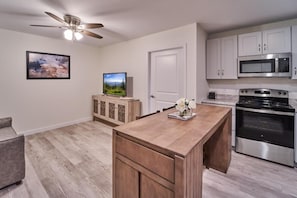 A modern kitchen with a wooden island, stainless steel appliances, and a ceiling fan. - The Ruby 212 (Pigeon Forge)