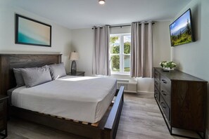 A bedroom with a bed, a nightstand, a dresser, a TV, and a window with curtains. - The Ruby 212 (Pigeon Forge)