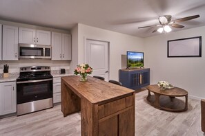 A modern kitchen with stainless steel appliances, a wooden island, and a ceiling fan. - The Ruby 213 (Pigeon Forge)