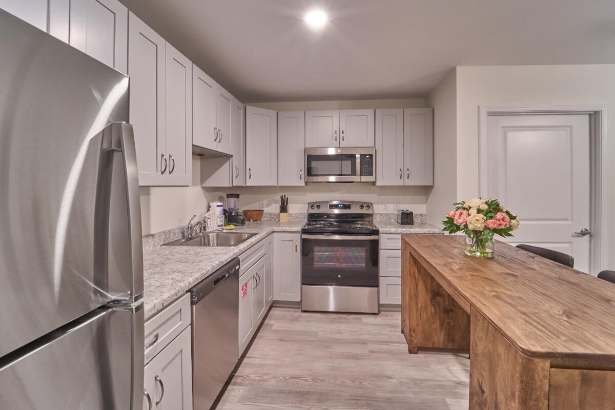 A modern kitchen with stainless steel appliances, white cabinetry, and a wooden island.