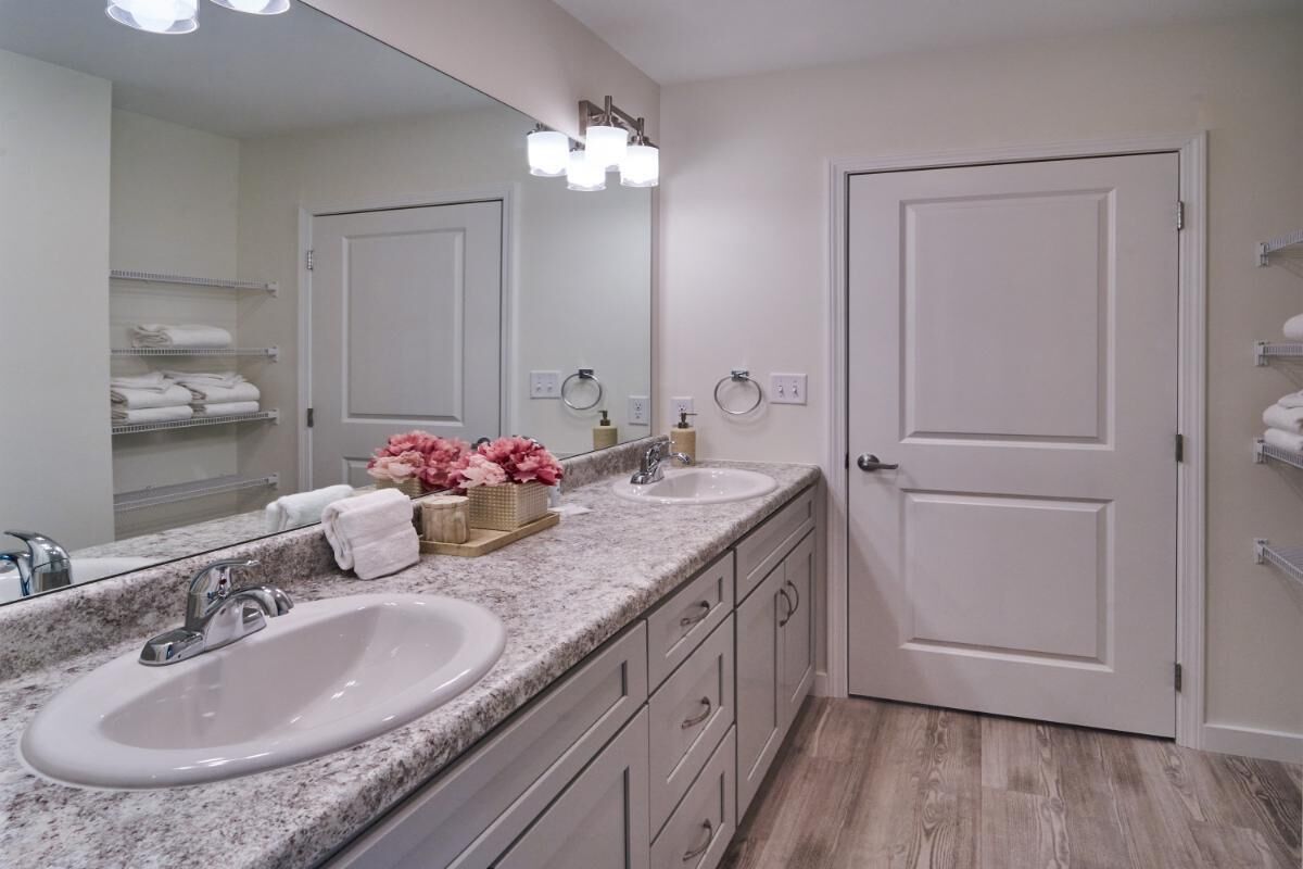 A bathroom with two sinks, a large mirror, and a door.