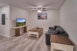 Ein Wohnzimmer mit Deckenventilator, Fernseher auf einem Schrank, einer Couch und einem Couchtisch.
