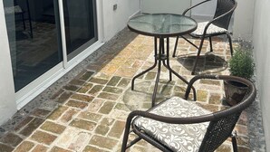 Een terras met een glazen deur, een witte deur en een kleine tafel met stoelen.