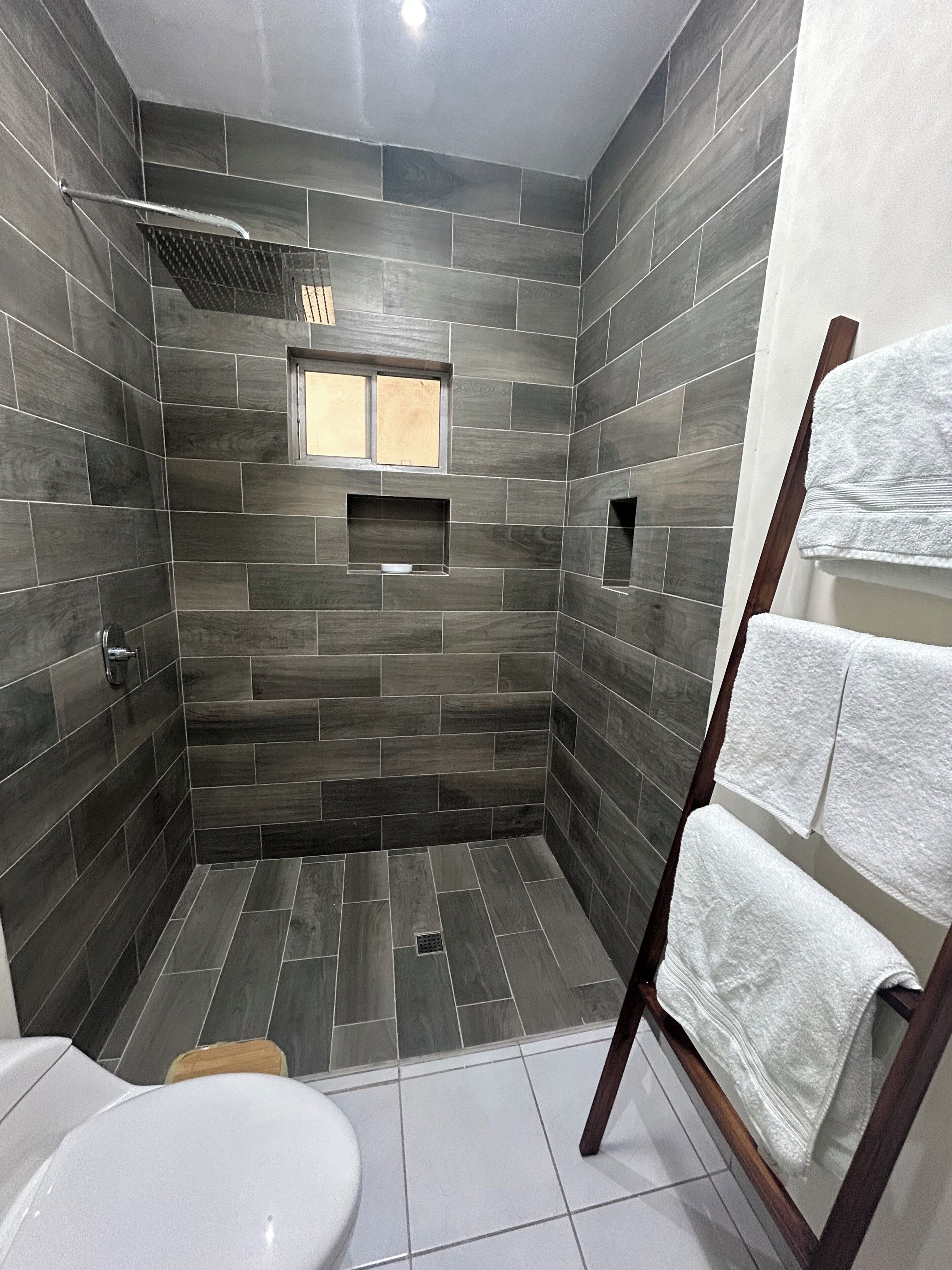 A modern bathroom with a shower, a toilet, and a towel rack.. Full House Steps from BBVA Stadium