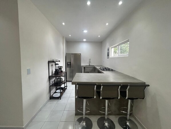 A kitchen with a central island, a refrigerator, and a window.