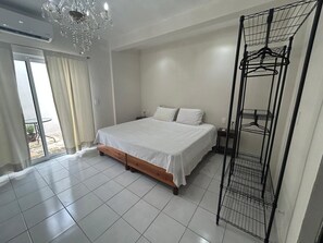 Une chambre à coucher avec un lit, un lustre, une armoire et un balcon.