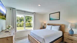 A bedroom with a bed, bedside tables, a dresser, a window with curtains, and a painting on the wall. - The Ruby 300 (Pigeon Forge)