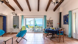 Amplia habitación con comedor, una estantería y vista al mar.