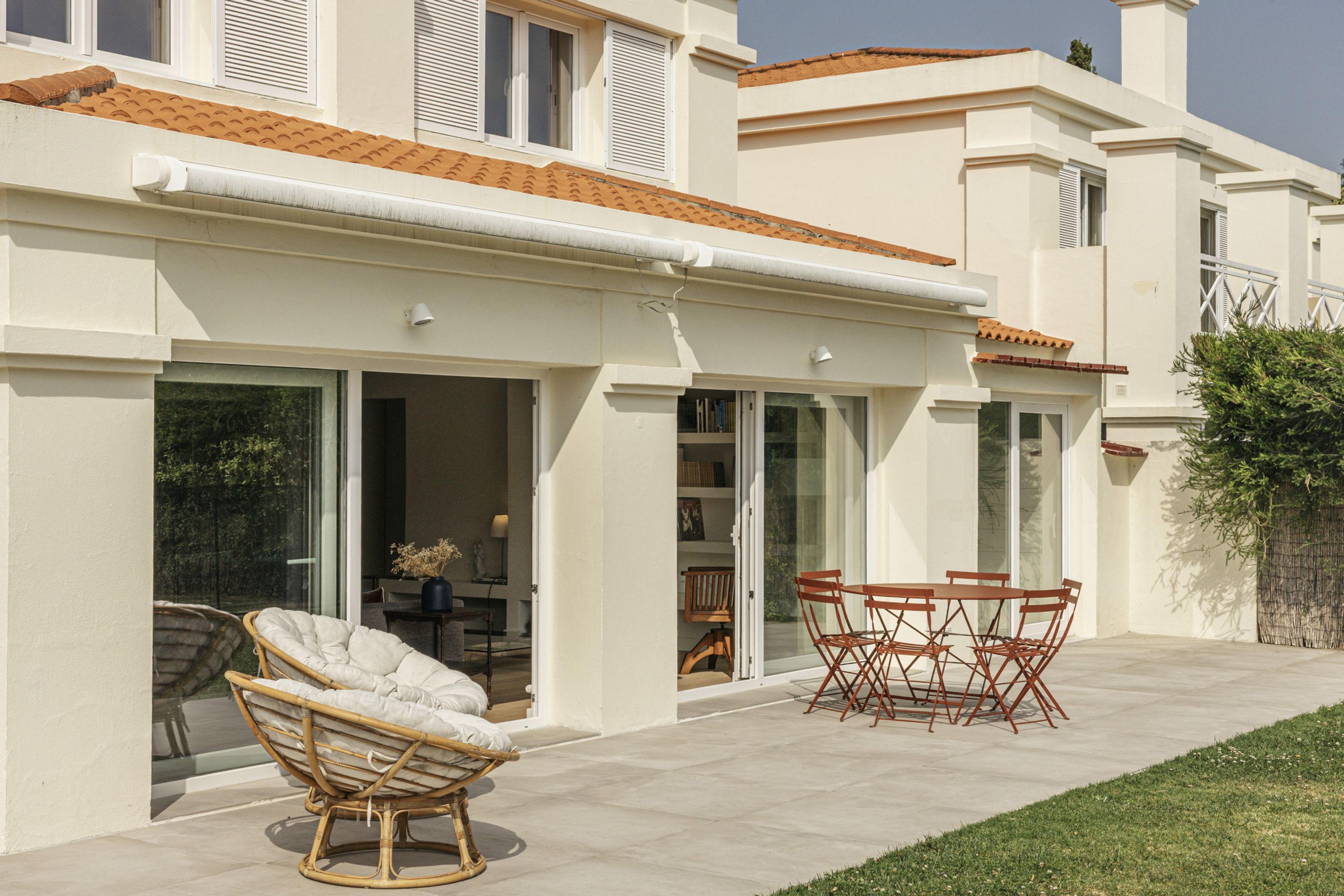 Ein Haus mit Terrasse, einem Esstisch und einem Korbstuhl.