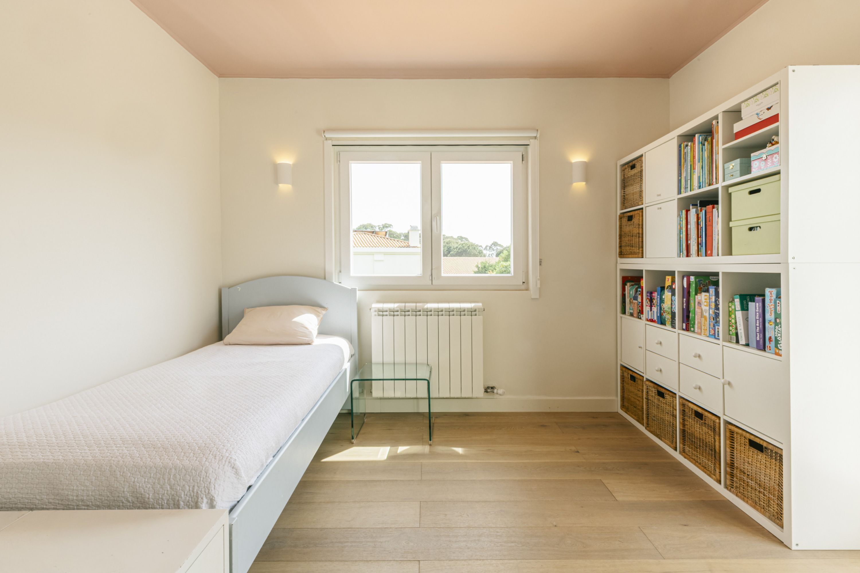 Ein Schlafzimmer mit einem Bett, einem Fenster, einer Heizung und einem Bücherregal.