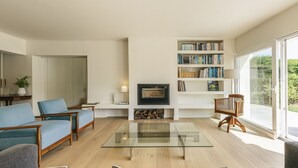 Ein modernes Wohnzimmer mit Kamin, Bücherregalen und einem großen Fenster.