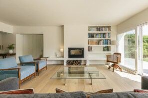 Una sala de estar moderna con chimenea, estanterías y un ventanal grande.
