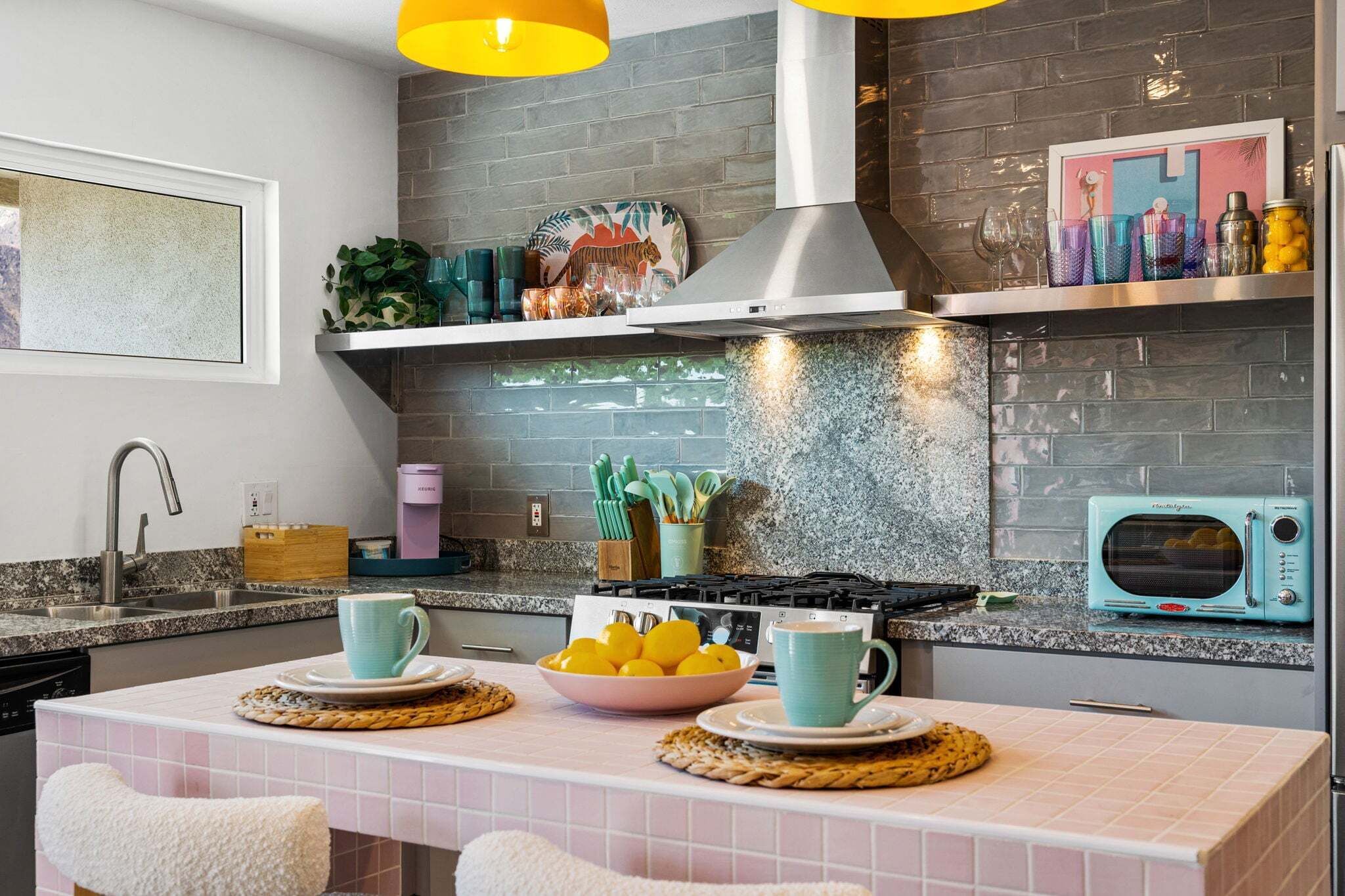 Een moderne keuken met een granieten aanrecht, een gasfornuis, een magnetron en een hangende lamp.