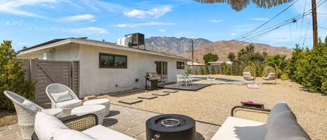 Un patio con mobiliario exterior, una parrilla y vista a la montaña.
