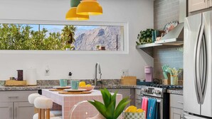 Una cucina moderna con vista sulle montagne, un frigorifero in acciaio inossidabile e un'area pranzo con tavolo e sedie.