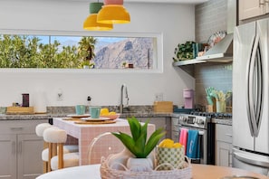 Eine moderne Küche mit Blick auf Berge, einem Edelstahlkühlschrank und einem Essbereich mit Tisch und Stühlen.
