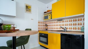 Une cuisine compacte équipée d’un four à micro-ondes, d’un four et d’un évier, ainsi qu’une petite table à manger avec des chaises et un crédence décorée.