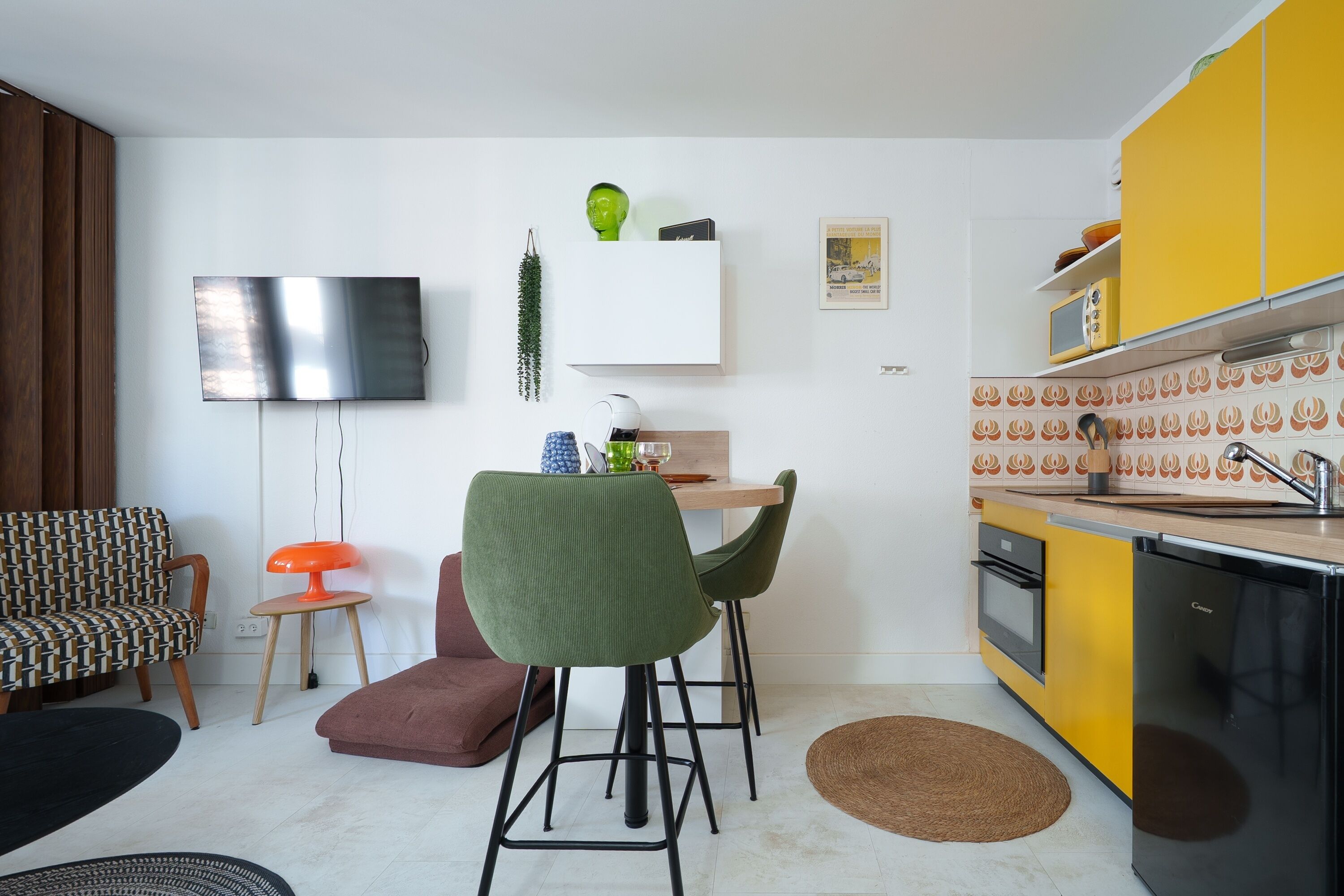 Una cucina moderna con mobili gialli, un frigorifero nero e un'area pranzo con tavolo e sedie.