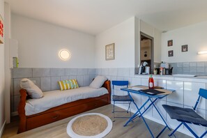Ein gemütlicher, kleiner Wohnraum mit einer Couch, einem Esstisch und einer Küchenzeile.
