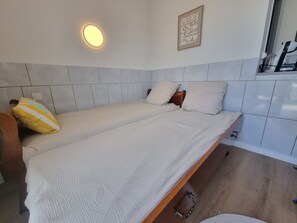 Ein Einzelbett mit Kopfteil, ein Nachttisch und eine Wandleuchte.