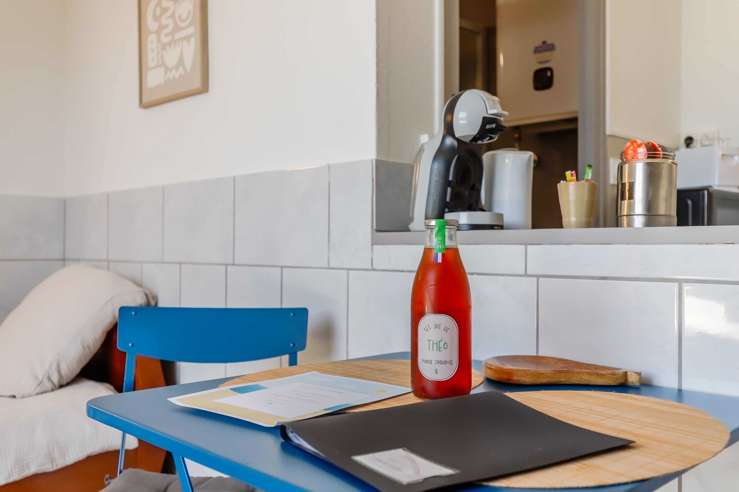 A kitchen with a table, chair, and a bottle of sauce.